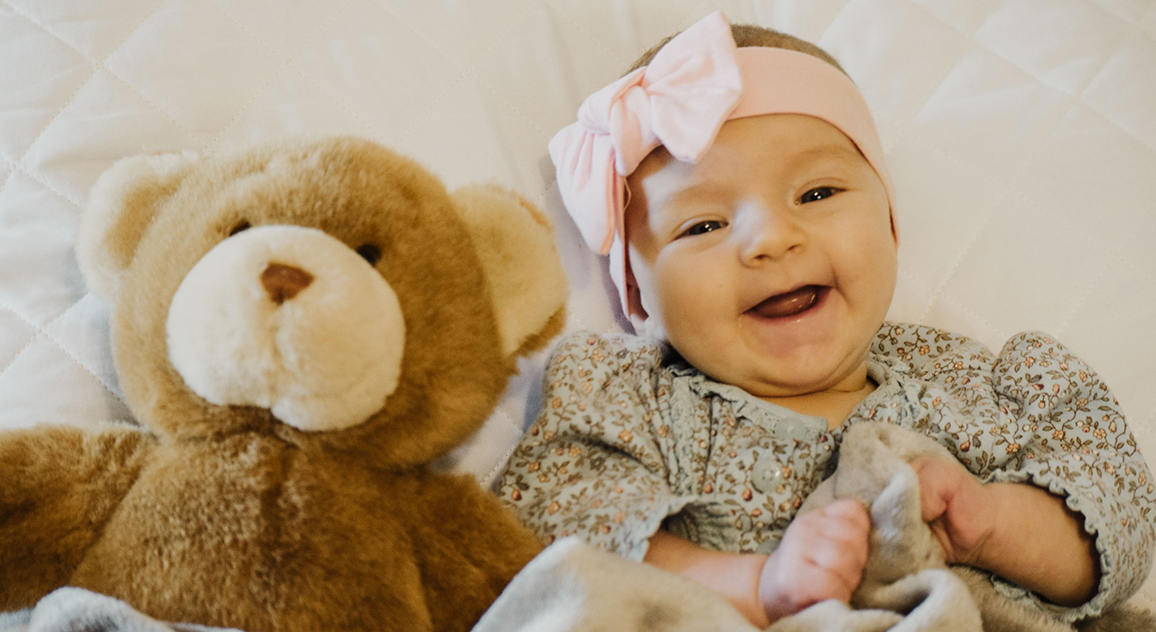 クマのぬいぐるみと一緒に寝る赤ちゃん